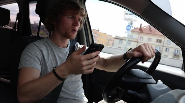 Young driver suddenly brakes while holding a smartphone after losing attention on road as distracted driving creates a dangerous traffic situation in the busy city street