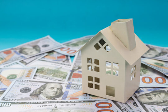Mortgage Financial Concept with Miniature Model on Stack Dollar Over Blue Background
