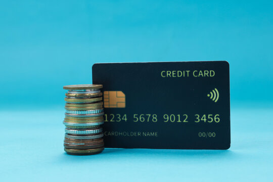 Closeup of Stacked Coins with Credit Card Over Blue Background