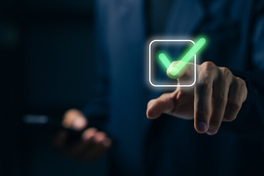 Business professional pressing a green check mark on virtual interface, representing approval, verification, validation, confirmation, compliance, quality control, and digital workflow.