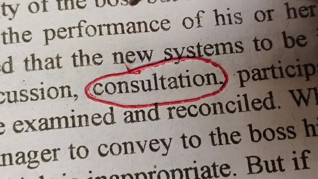 Hand with red ink pen marking and highlighting consultation word or text printed on news article or magazine page. Importance of business, medical and mental health consultation concept.