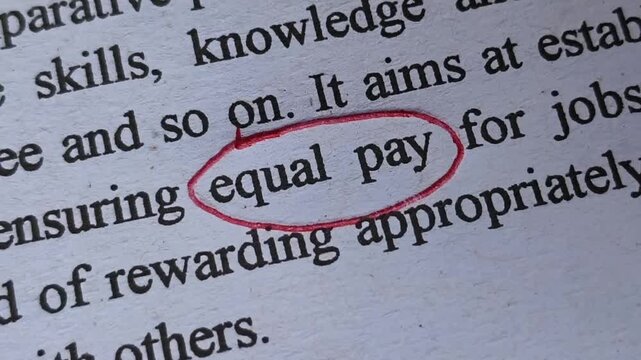 Closeup of employee or entrepreneur woman hand with pen emphasize or  highlight equal pay word printed on news article or magazine. Women facing gender and payment discrimination in workplace concept.