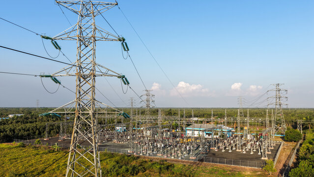 Electrical transmission towers and a power substation situated in a lush tropical rural area
