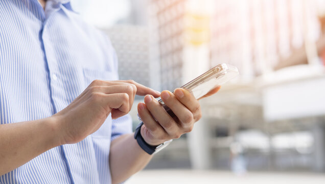 close up businessman hand hold smartphone check work or mail on website while stay in the city for business technology concept