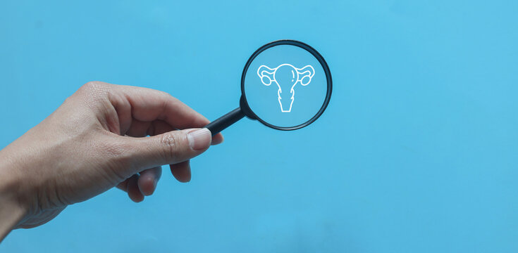 close up woman hand hold magnify with uterus symbol on blue background represent about women health checkup and lifestyle for health and wellness concept