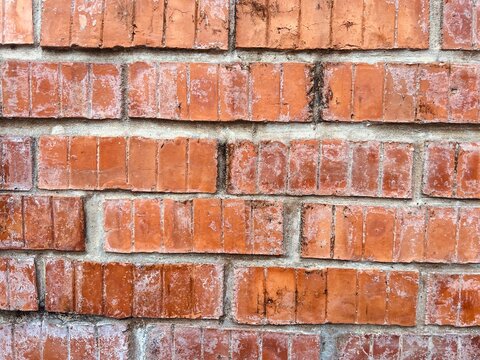Extreme close-up view of a rustic red brick wall showcasing detailed surface textures, vertical grooves, and weathered characteristics.