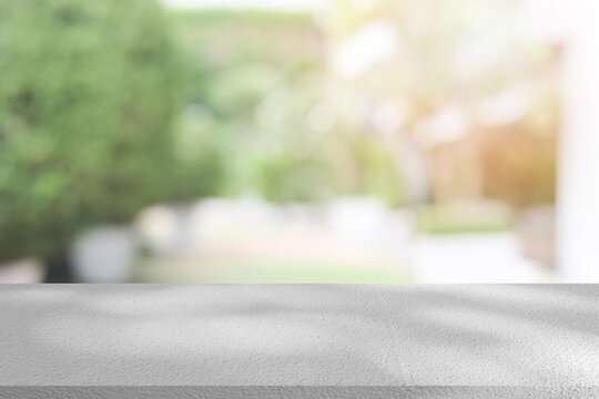 abstract blurred garden view form living room window with modern plain concrete table counter background for show , promote ,design banner ads on display concept