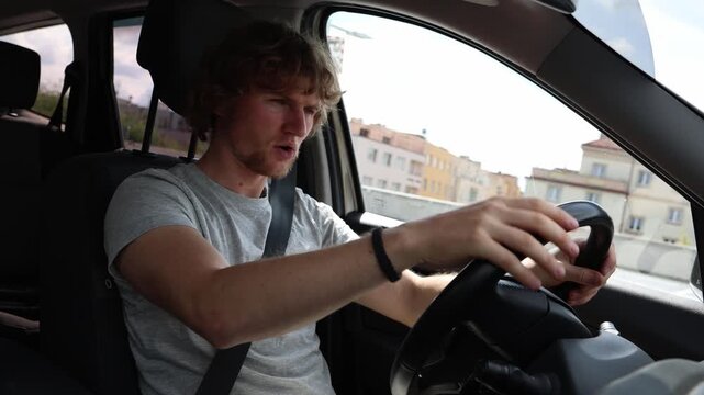 Sleepy young driver struggles to stay awake on the road touching his face and trying to wake himself up as fatigue and drowsiness make driving increasingly dangerous also