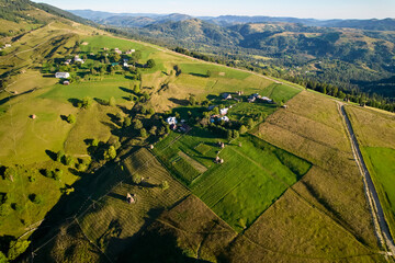 Naklejka premium Aerial view of picturesque rural landscape at sunrise, with rolling hills and lush green fields.