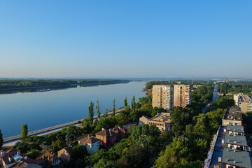 Naklejka premium Elevated panoramic view of Vidin, Bulgaria, featuring residential apartment blocks, a tree-lined boulevard and the urban landscape extending toward the horizon on a sunny summer day. Drone view