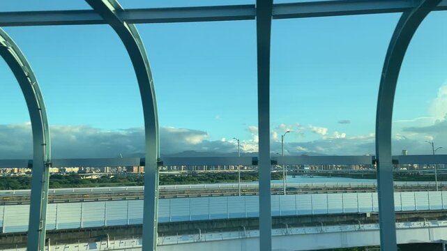 Scenic view of a modern cable-stayed bridge and city skyline from an airport train window at sunset in Taiwan 대만 타오위안 공항철도(MRT)