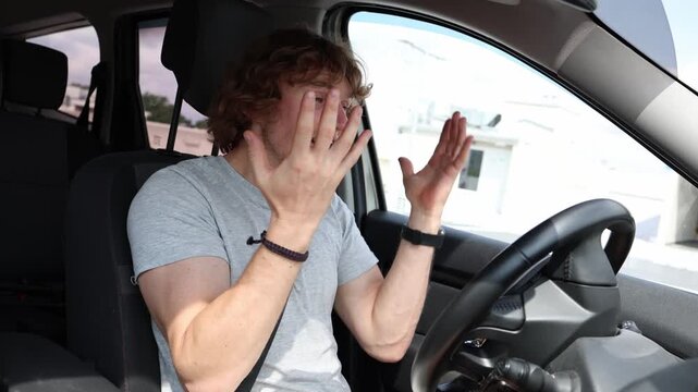 Confused young driver becomes nervous while driving through the city gesturing with his hands and looking frustrated as he struggles to understand the situation on the road