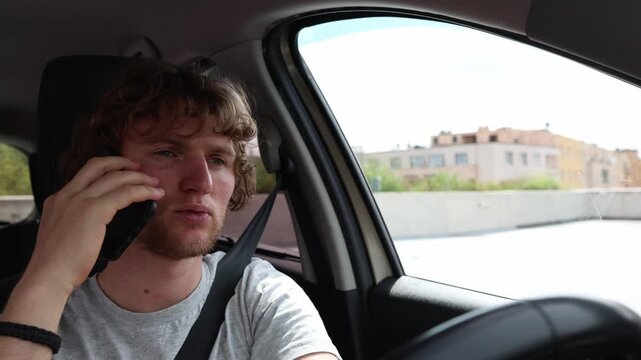 Phone conversation creates dangerous traffic situations as a distracted young driver talks on smartphone while driving and loses focus on the busy city road ahead of hims