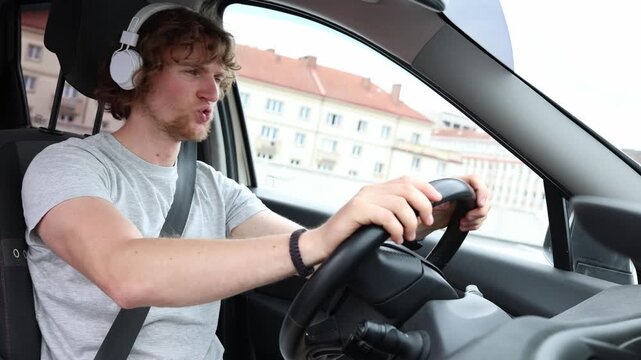 Driver listens to music through headphones and sings along inside his car enjoying a lively personal moment while holding the steering wheel and getting lost in his favorite song