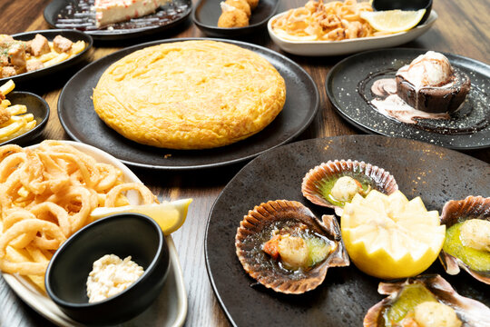 Table filled with various spanish tapas and dessert dishes for a shared meal
