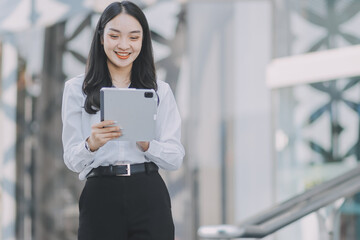 Obraz premium Young professional woman talking on phone and holding coffee outside modern office building
