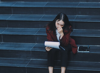 Fototapeta premium desperate Asian Korean business woman crying alone sitting on street staircase suffering stress and depression crisis being victim of mobbing or fired losing her job