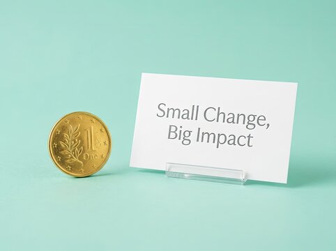 Small gold coin next to a card with Small Change Big Impact text ideal for finance media symbolizing how small investments yield huge results