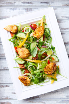 Salad with Chicken Breast, Cherry Tomatoes, Cucumber and fresh Basil. Bright wooden background. Top view. 