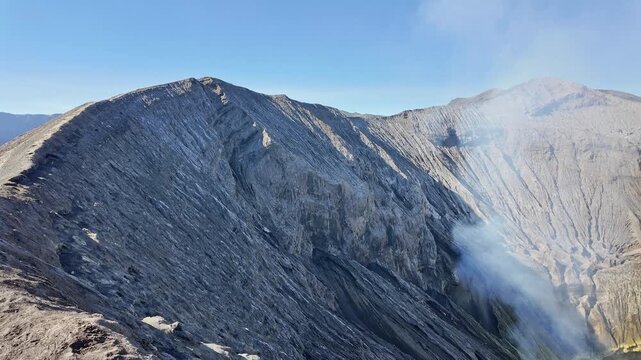 Horizontal pan from left to right along the rim of Mount Bromo, revealing the expansive smoking crater interior and volcanic gas, Bromo Tengger Semeru National Park, Indonesia