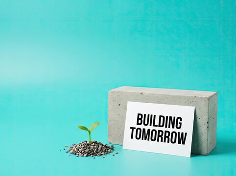 Green seedling next to concrete block with Building Tomorrow text ideal for corporate growth content symbolizing sustainable future foundation