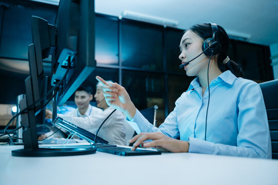 Asian engineer in headset analyzes radar screens and takes notes in a high tech control room