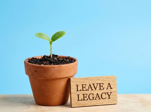 Green sprout growing in terracotta pot near leave a legacy sign suitable for leadership media representing long term impact and future growth