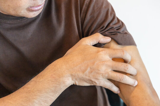 hand of asian senior man scratching his itchy arm from a mosquito bite or skin rash at home, allergic reaction concept indoor scene