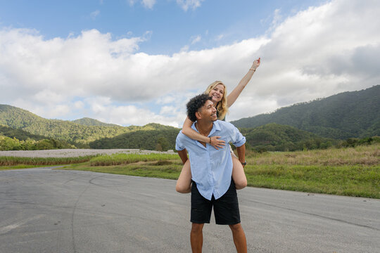 Man gives a woman a piggyback ride on a country road in Queensland
