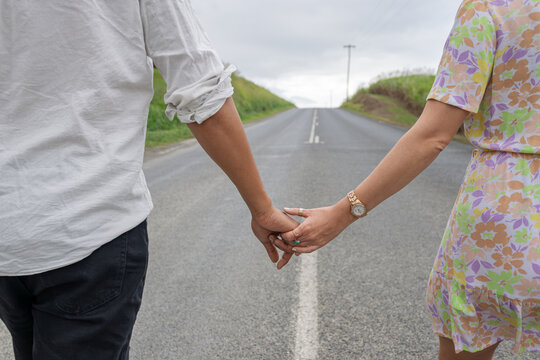 Young mixed race couple holding hands on the road