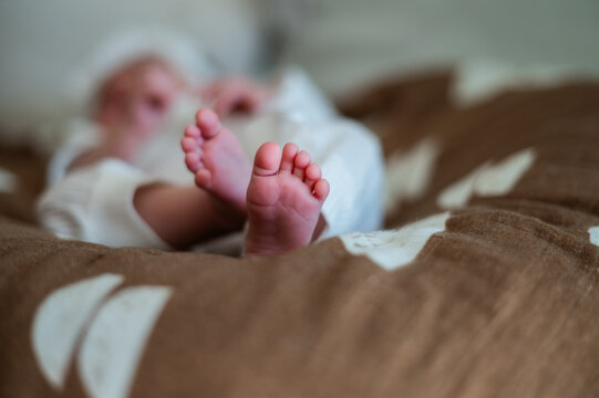 Close-up of a newborns tiny feet resting on a soft brown blanket