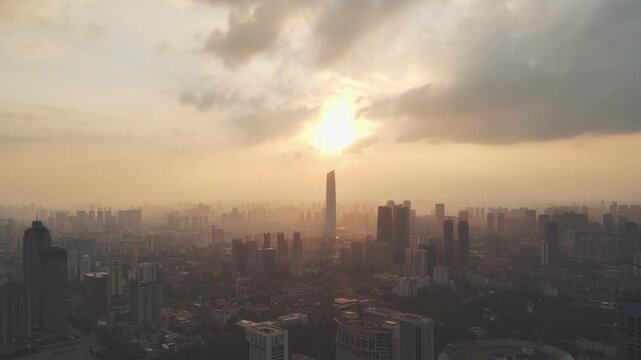 Hazy sunset over modern city skyline with dramatic clouds