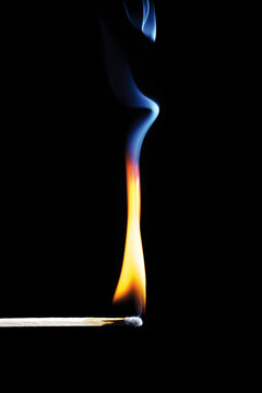 Burning match on black background, close-up