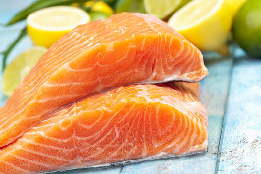Salmon fillets (Salmo salar) and lemons on blue wooden table