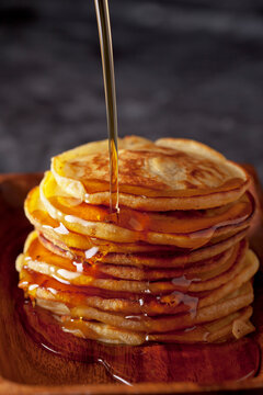 Maple syrup pouring over a stack of homemade pancakes