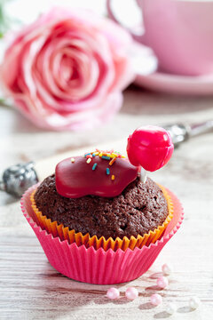 Chocolate muffin in muffin paper decoratet with red lolly and sugar icing on laid table
