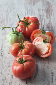 Whole and sliced Silesian raspberry tomatoes (Solanum lycopersicum), studio shot