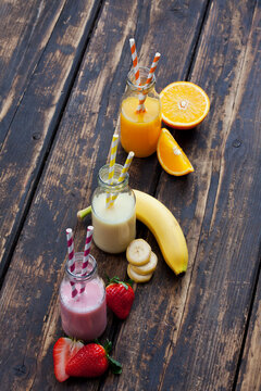 Row of three bottles with different fruit smoothies and orange juice
