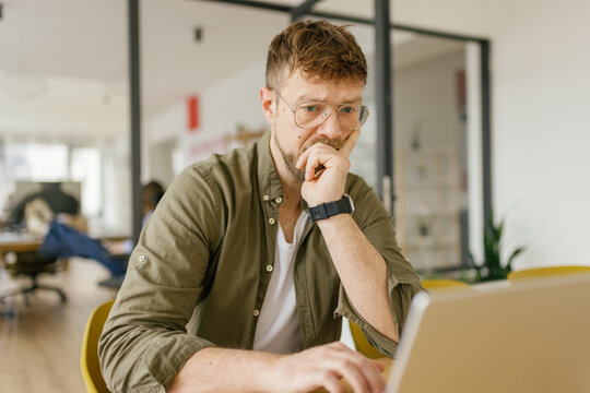Serious man analyzes business problem on laptop in the office
