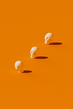 Three 3D cartoon skulls cast shadows on an orange background