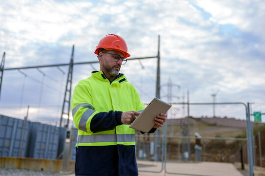 Engineer working outdoors at power plant using digital tablet