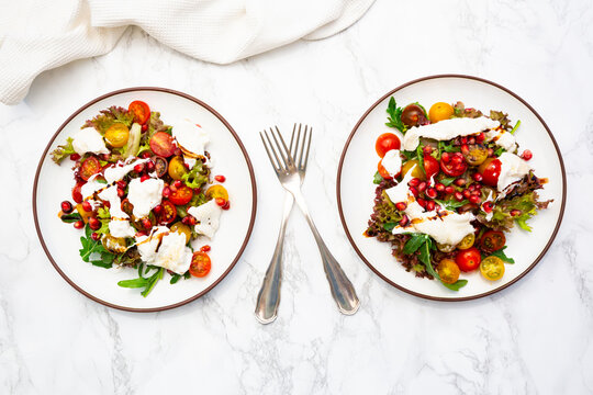Two plates feature fresh burrata salad with tomato and pomegranate