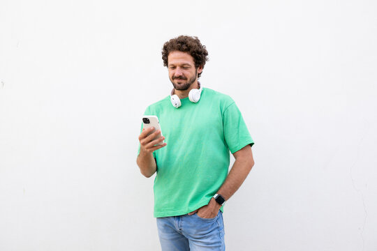 Man wearing a headphone uses a smartphone on a white background