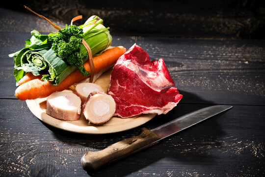 Soup greens, cattle beef marrows and beef on chopping board, close up
