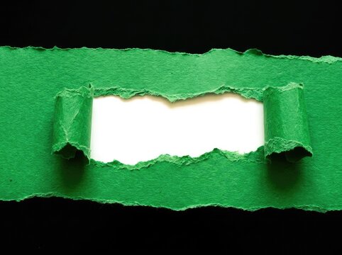 Torn green paper revealing white space on black suitable for banner designs symbolizing breakthrough discovery and uncovering new opportunities