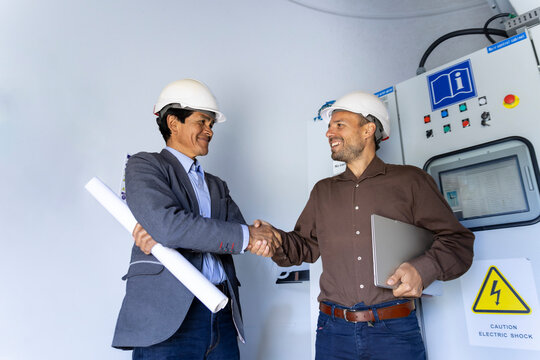 Engineer coworkers shake hands inside a wind turbine base in Ecuador