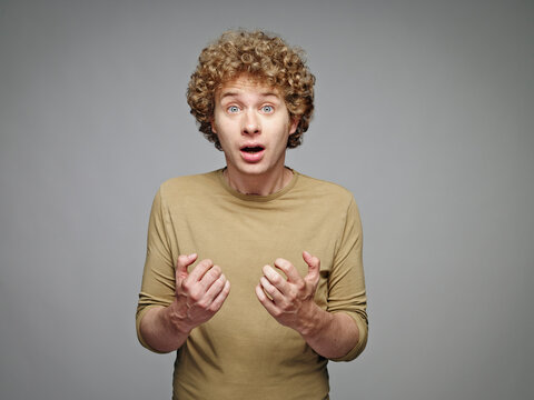 Portrait of astonished blond man in front of grey background