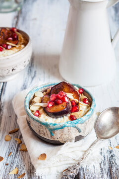 Porridge with cinnamon, millet, backed plum, pomegranate and roasted almond slivers