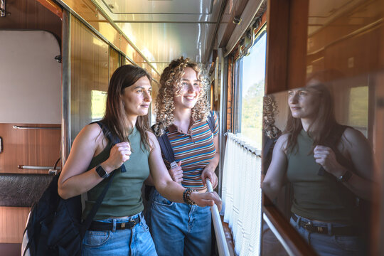 Female friends looking out train window during scenic journey
