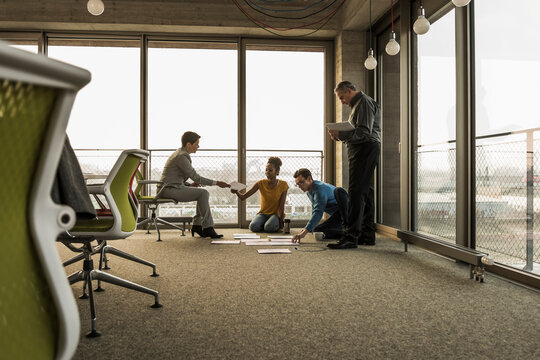 Businesspeople looking at documents on office floor